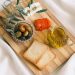 A delicious assortment of olives, cheese, tomatoes, and bread arranged on a wooden board.