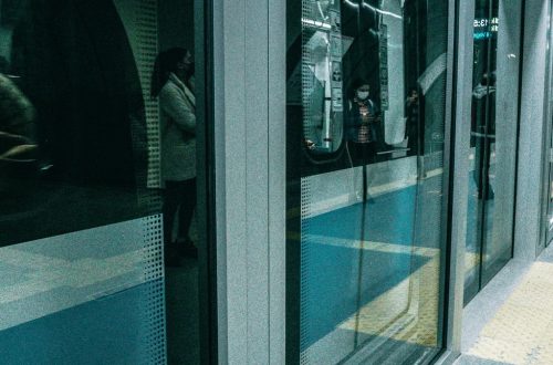 People waiting at Istanbul metro platform with reflections and modern architecture.